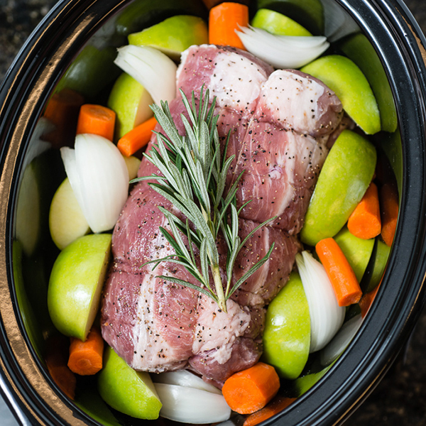 slow cooker filled with a pork loin with vegetables
